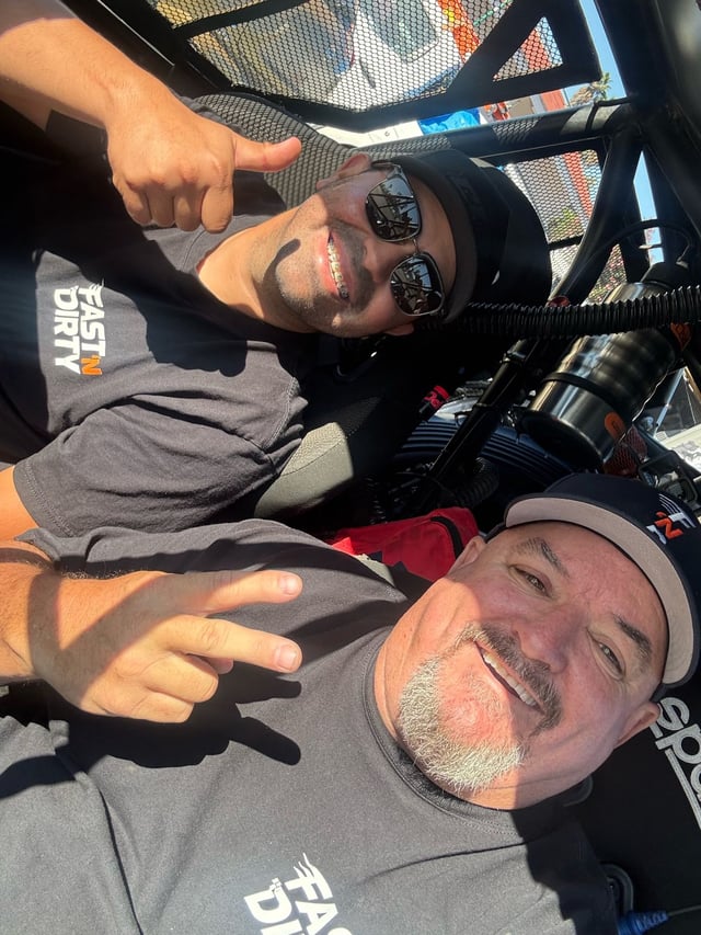 Two Fast 'N Dirty crew in the cab of the UTV, one giving a thumbs up, at NORRA 500 tech in Ensenada