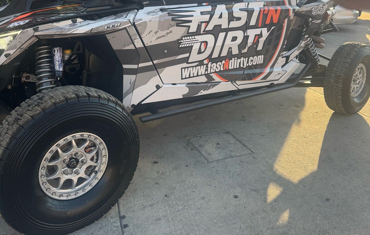 The Fast 'N Dirty UTV parked on pavement, side view of the wrap and front wheel