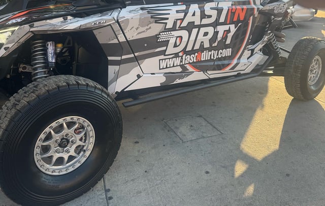 The Fast 'N Dirty UTV parked on pavement, side view of the wrap and front wheel