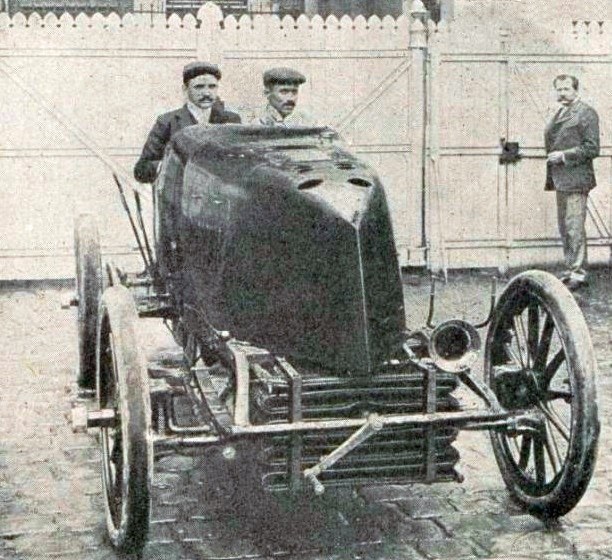 Mors racing car with two men aboard in a cobblestone yard before the 1903 Paris to Madrid race